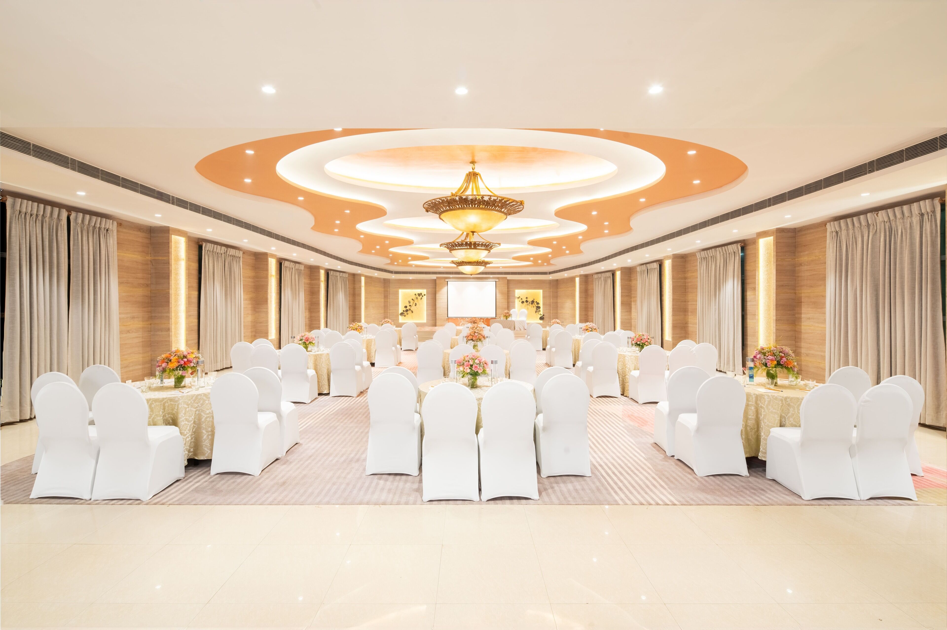 A conference room with a long table, white chairs, and a chandelier.