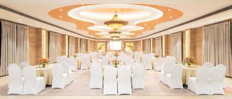 A conference room with a long table, white chairs, and a chandelier.