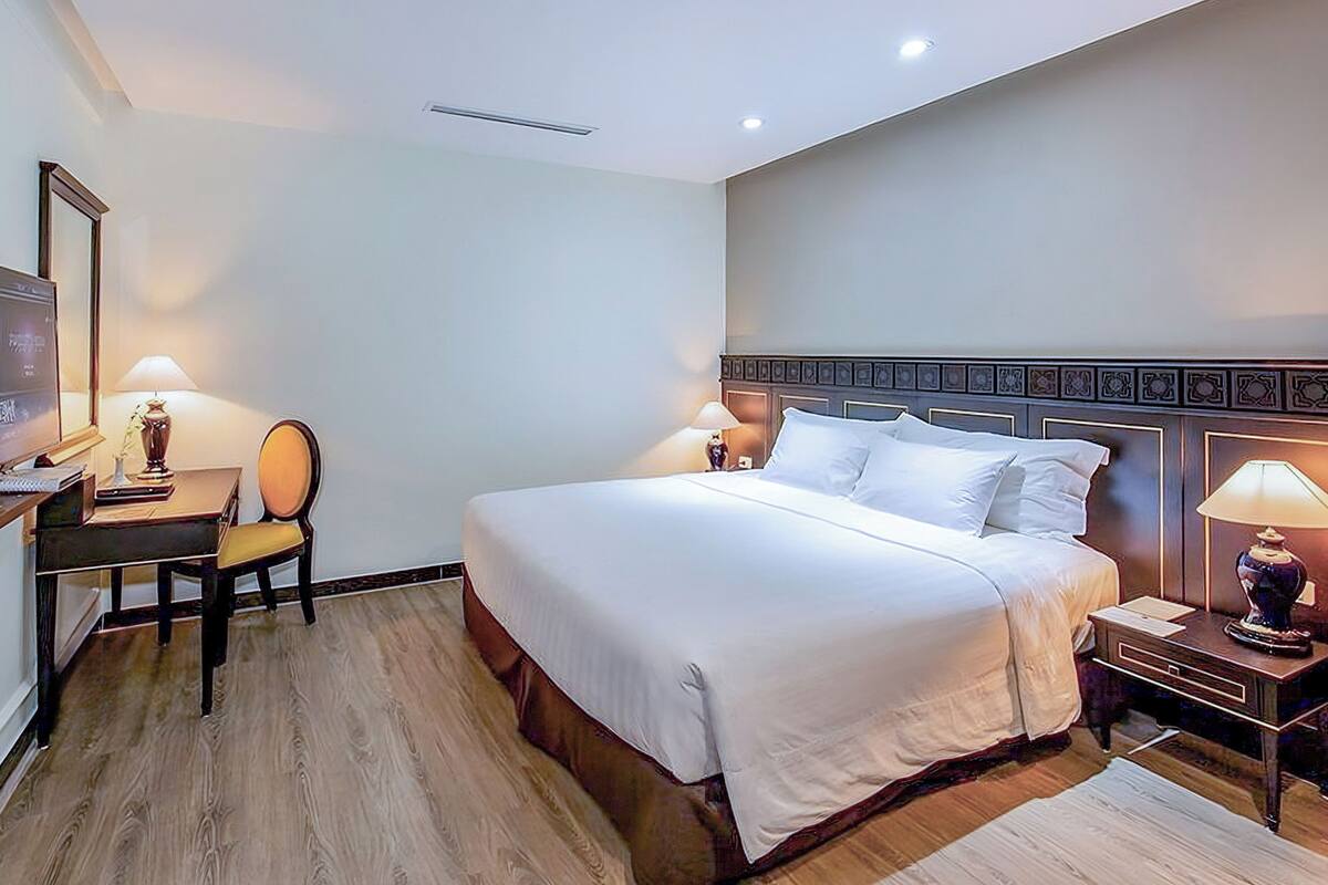 A hotel room with a bed, a desk, a chair, and a TV.