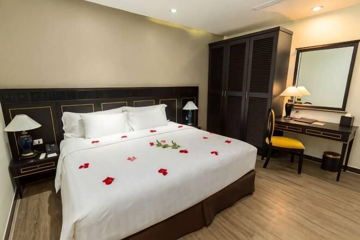 Une chambre d’hôtel comprenant un lit, des tables de chevet, un bureau, une chaise, un miroir et une armoire.