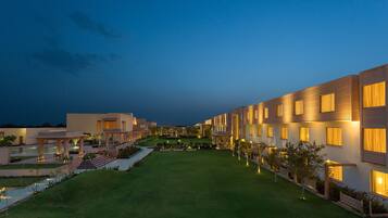 A modern hotel with a well-maintained courtyard, multiple balconies, and a clear view of the surrounding landscape.