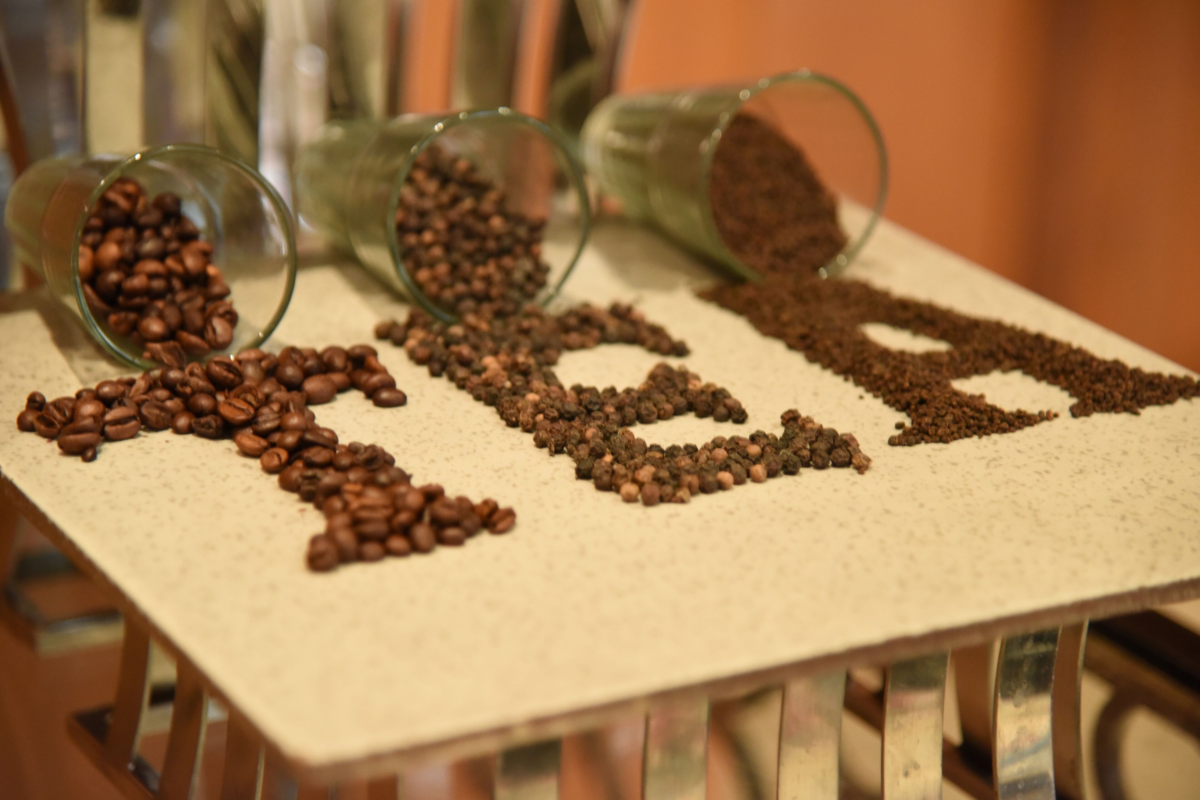 Uma mesa com grãos de café dispostos formando a palavra 'coffee'.