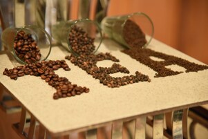 Una mesa con granos de café dispuestos para deletrear la palabra 'coffee'.