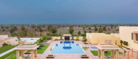 Un resort con piscina central, mobiliario exterior y vistas del paisaje circundante.