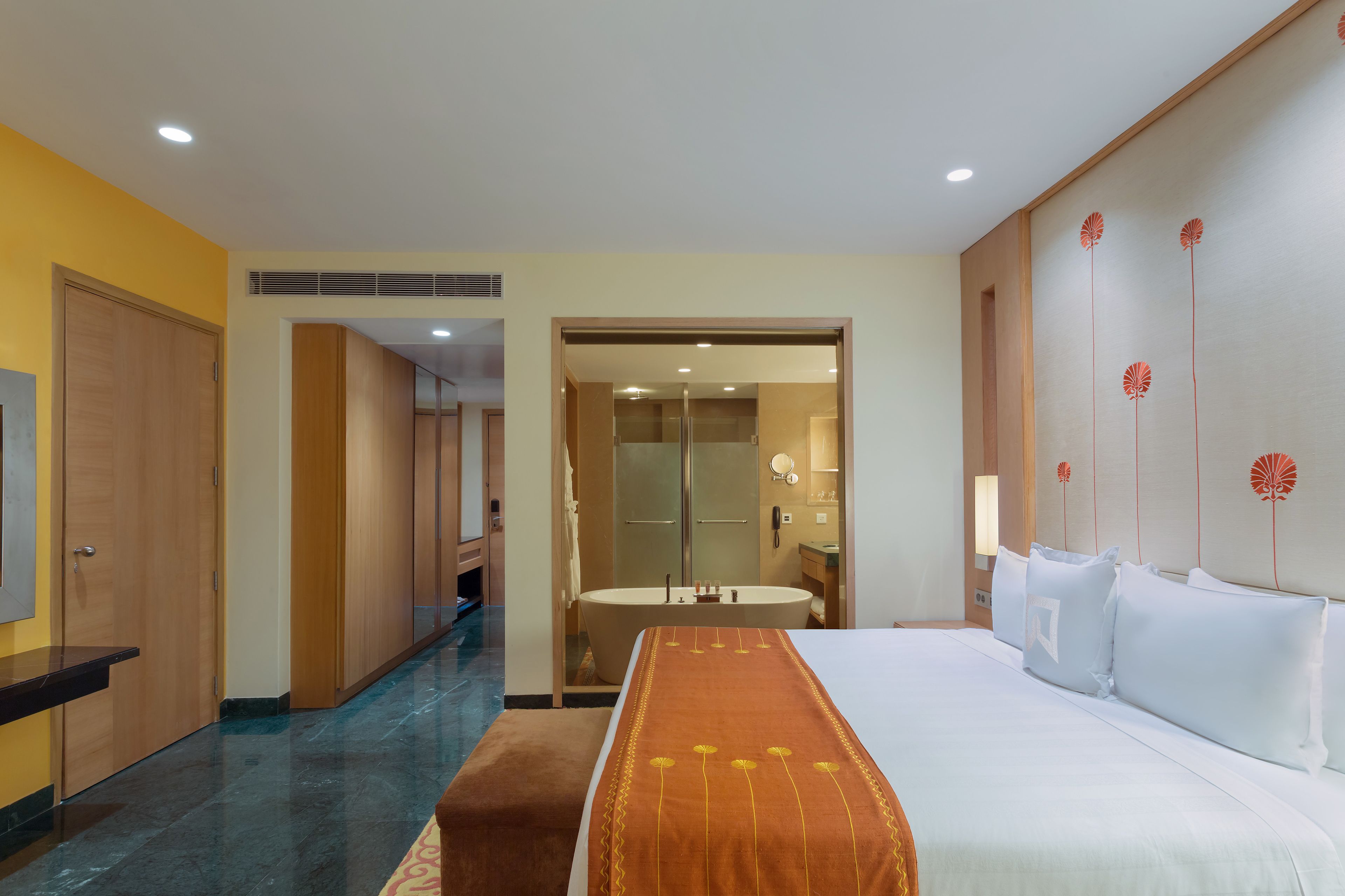 Habitación de hotel con una cama grande, un baño con bañera y un pasillo que da a otras habitaciones.