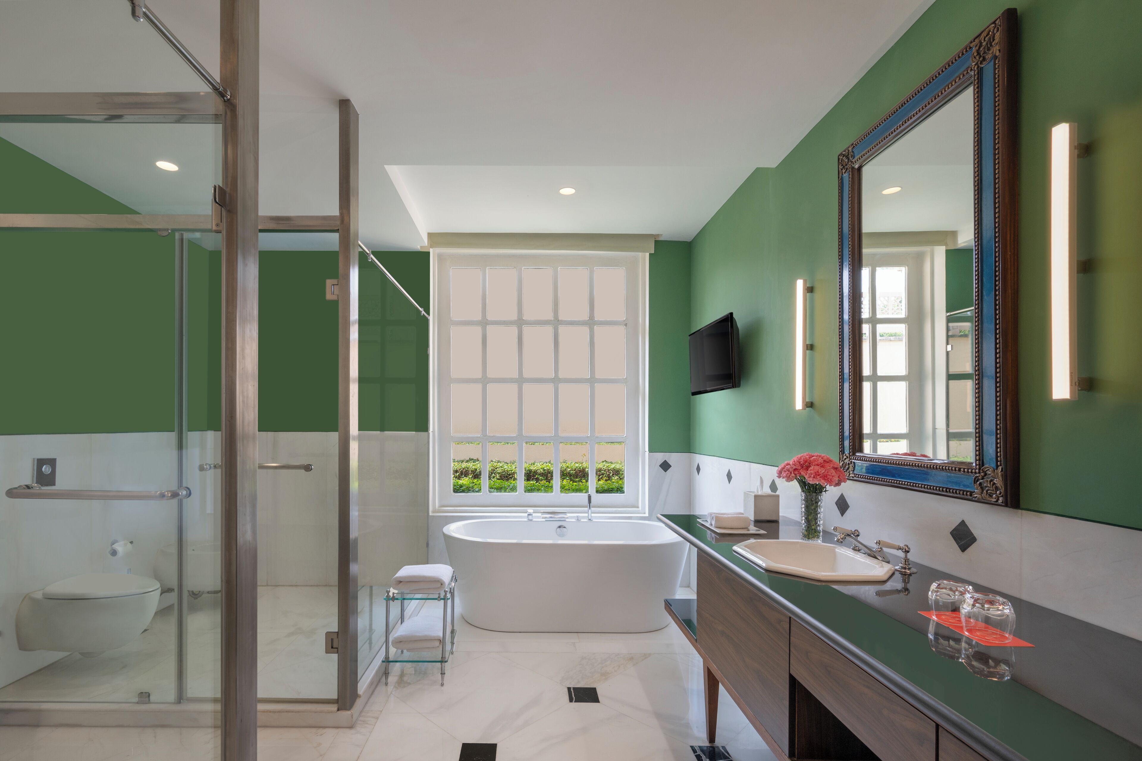 A modern bathroom with a glass-enclosed shower, a freestanding bathtub, and a vanity with a large mirror.