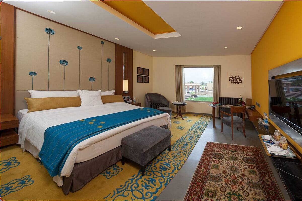 Een hotelkamer met een groot bed, een bureau, een televisie en uitzicht op de omgeving.