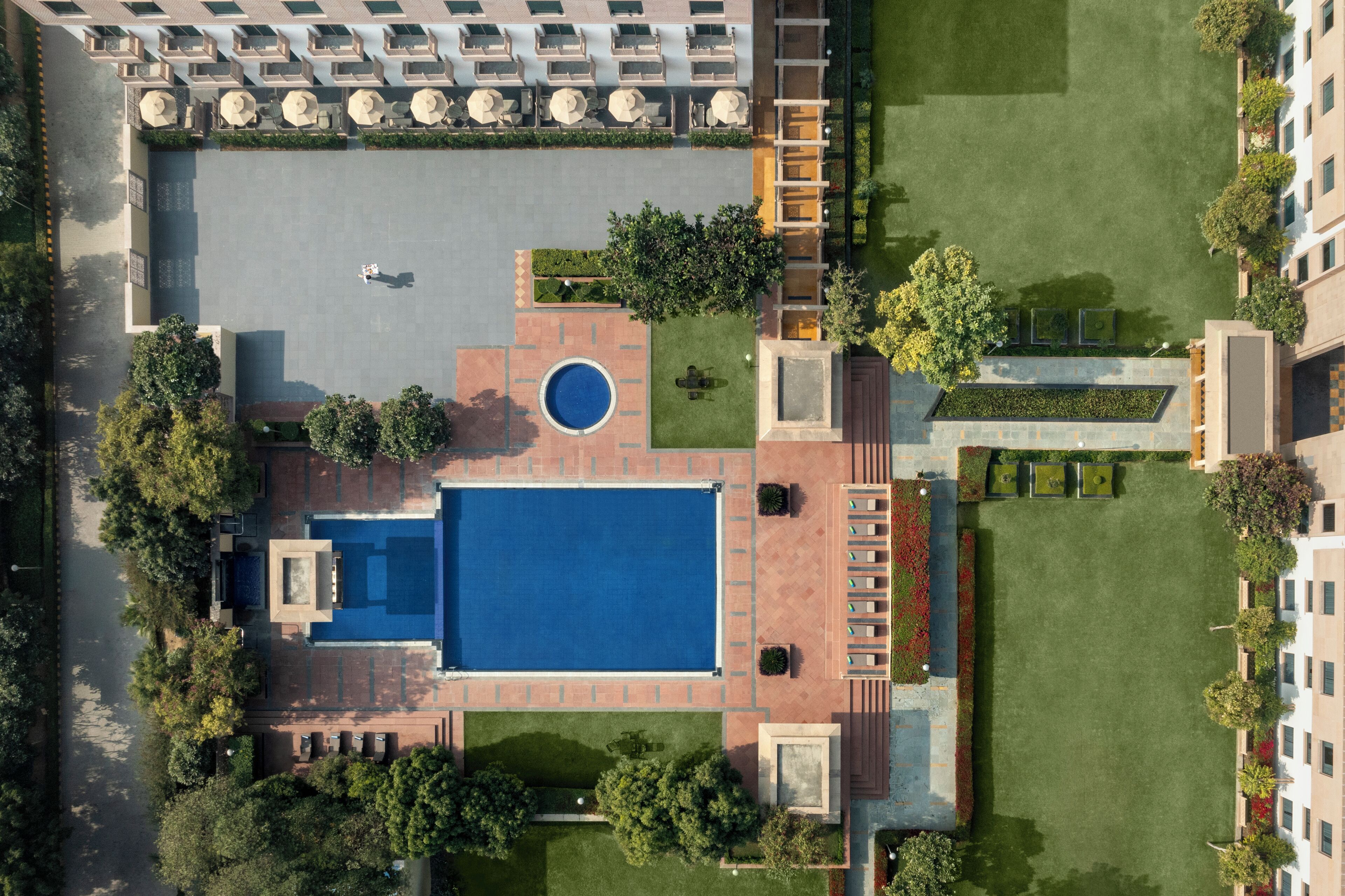 Vista aérea de um hotel com piscina, área de estar externa e jardins bem cuidados.