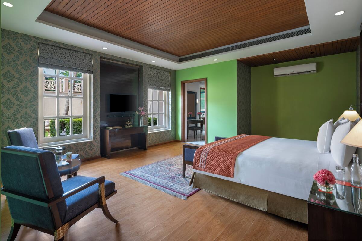Een slaapkamer met een groot bed, een televisie, een bureau en een stoel.