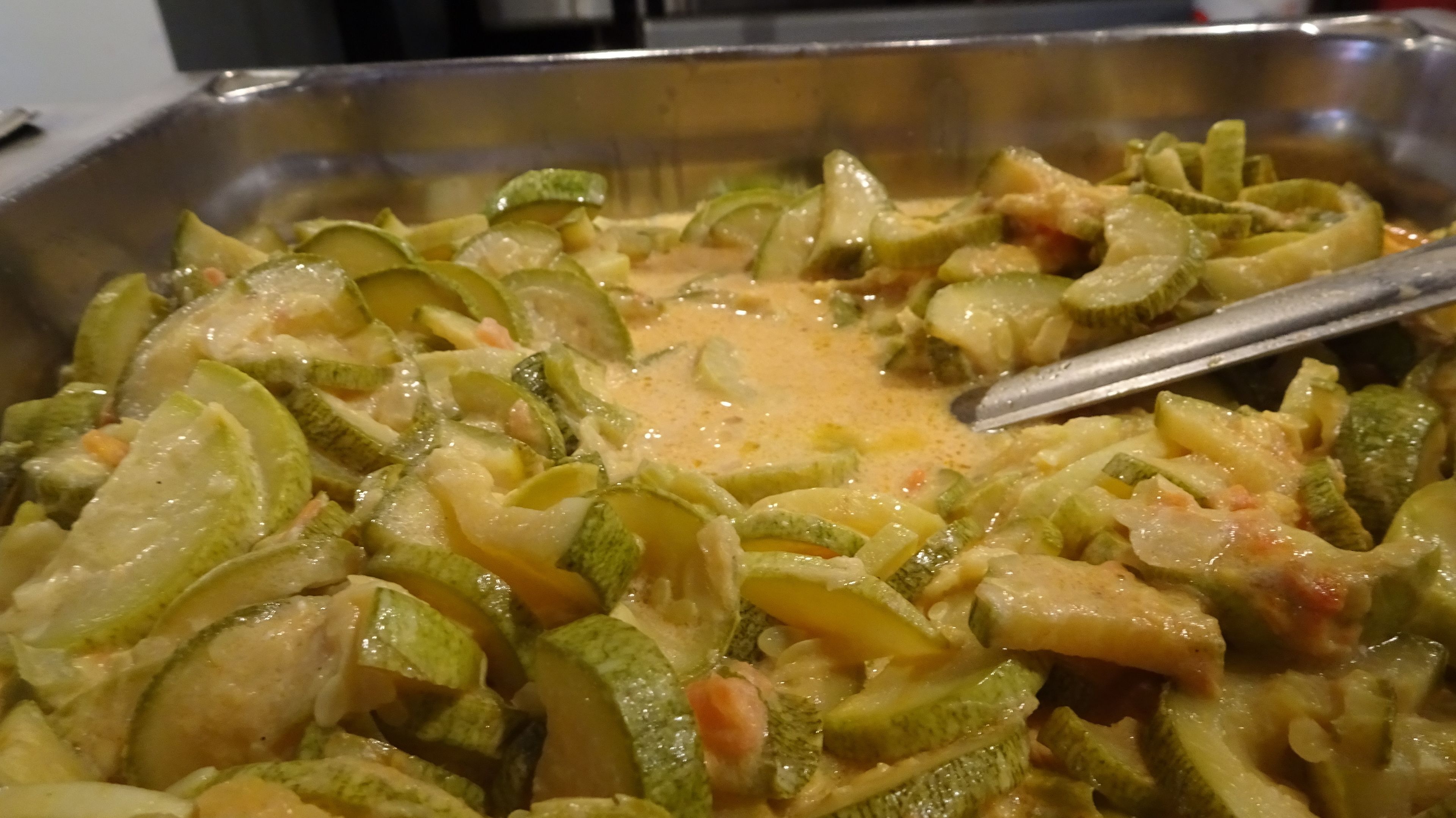 A buffet with a variety of dishes, including a creamy vegetable casserole.