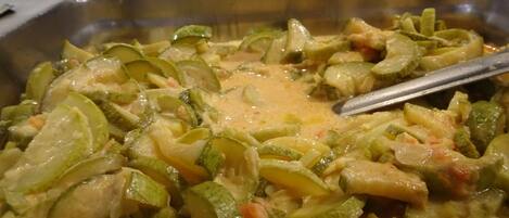 Un bufé con una variedad de platos, incluyendo un gratinado cremoso de verduras.