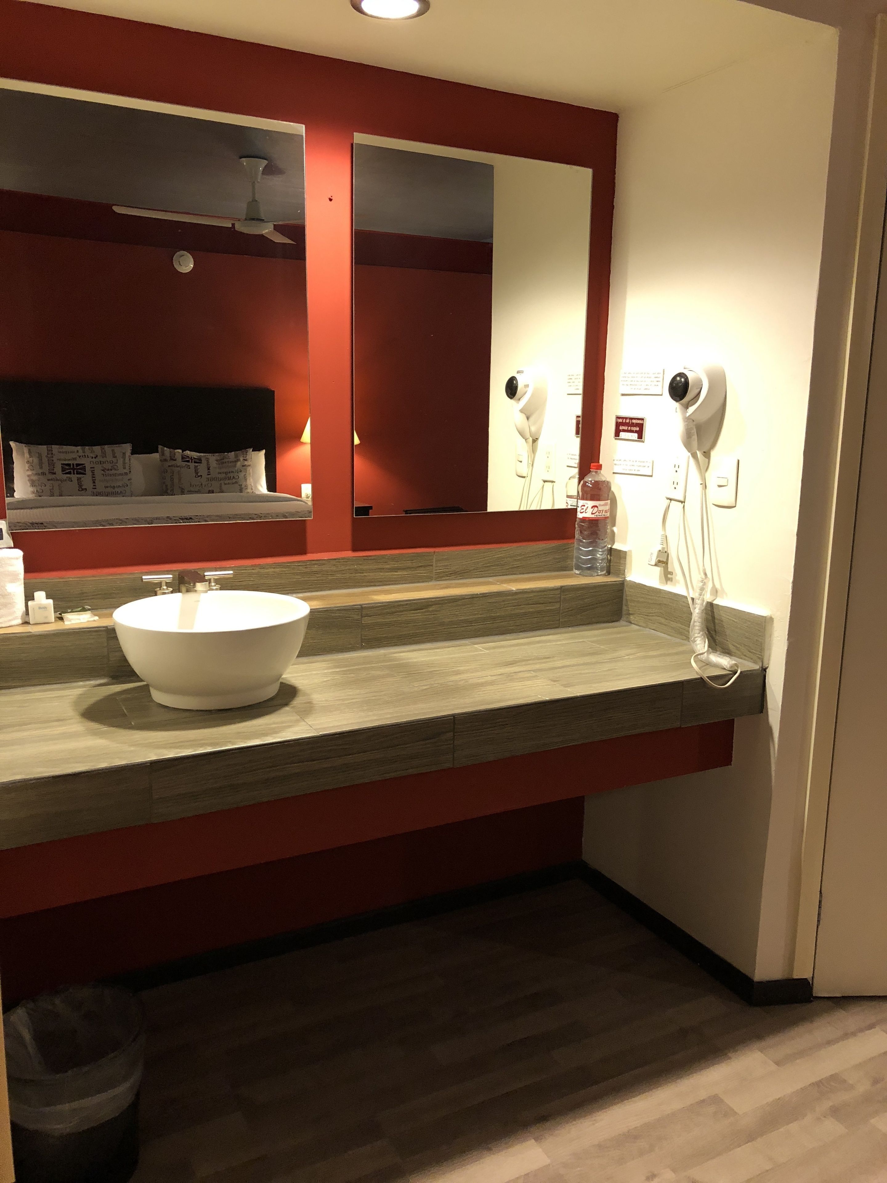 A bathroom with a large mirror, a white sink, and a hairdryer mounted on the wall.