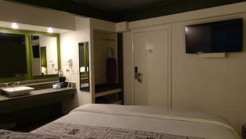 Een hotelkamer met een bed, een grote spiegel, een wastafel en een televisie.