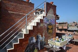 A mural on a brick wall with a staircase leading to an upper level. - Cosy Hotel (Bhaktapur)