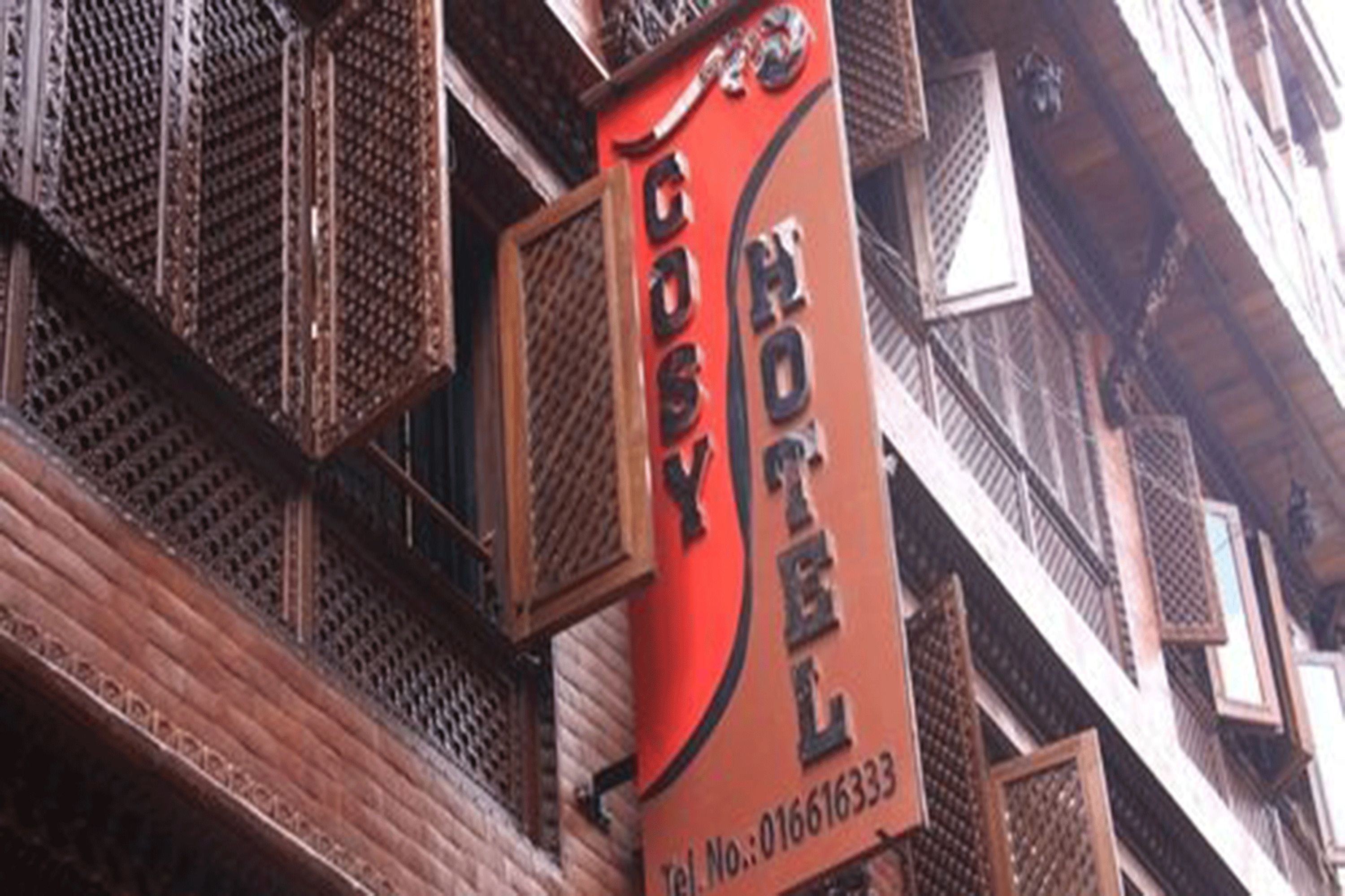 Señal de hotel con el nombre 'COSY HOTEL' y un número de teléfono.