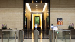 A lobby with a modern design, featuring a glass barrier gate, a digital information kiosk, and a poster on the wall. - Xingyi International Hotel Poly Store (Guangzhou)
