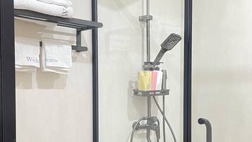 A modern bathroom with a glass-enclosed shower, a toilet, and a towel rack with folded towels.