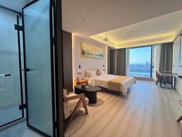 A modern hotel room with a large bed, a desk, and a view of the city. - Xingyi International Hotel Poly Store (Guangzhou)