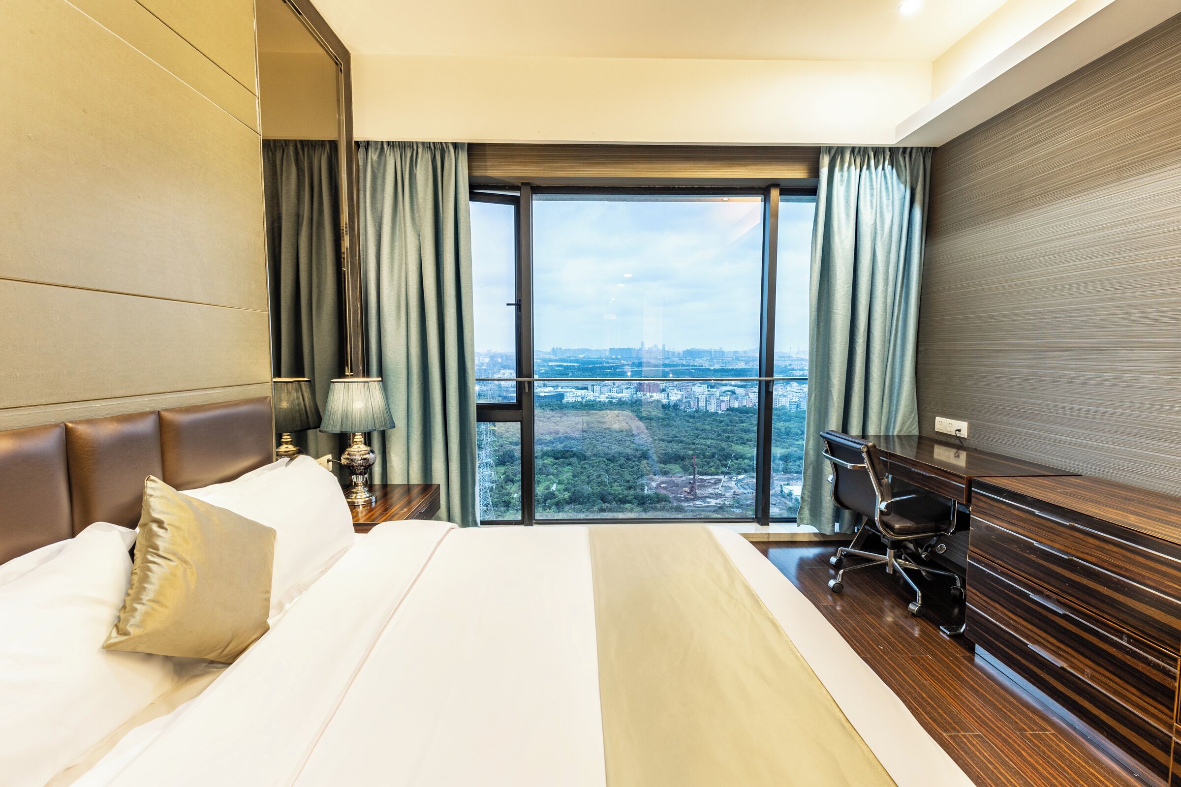 A hotel room with a large bed, a desk, and a view of a cityscape.
