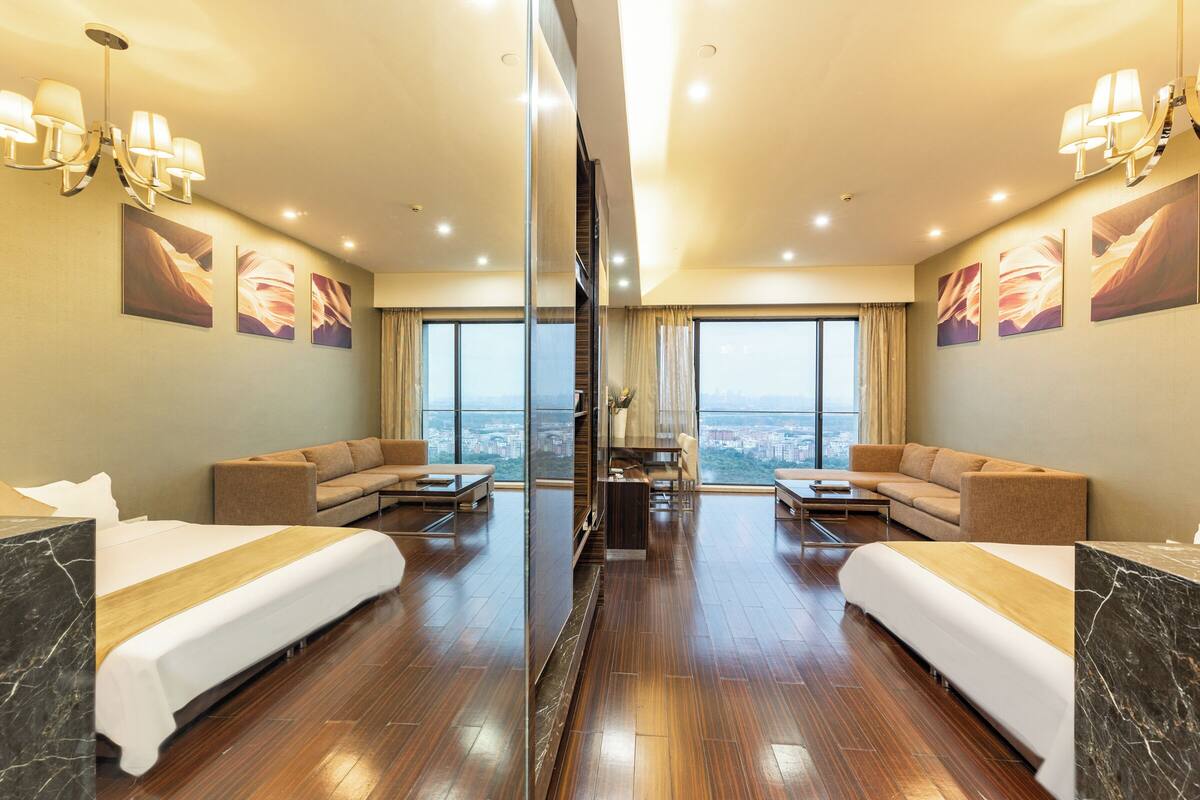 Habitación de hotel con dos camas, un sofá, una mesa de centro y vistas a la ciudad.