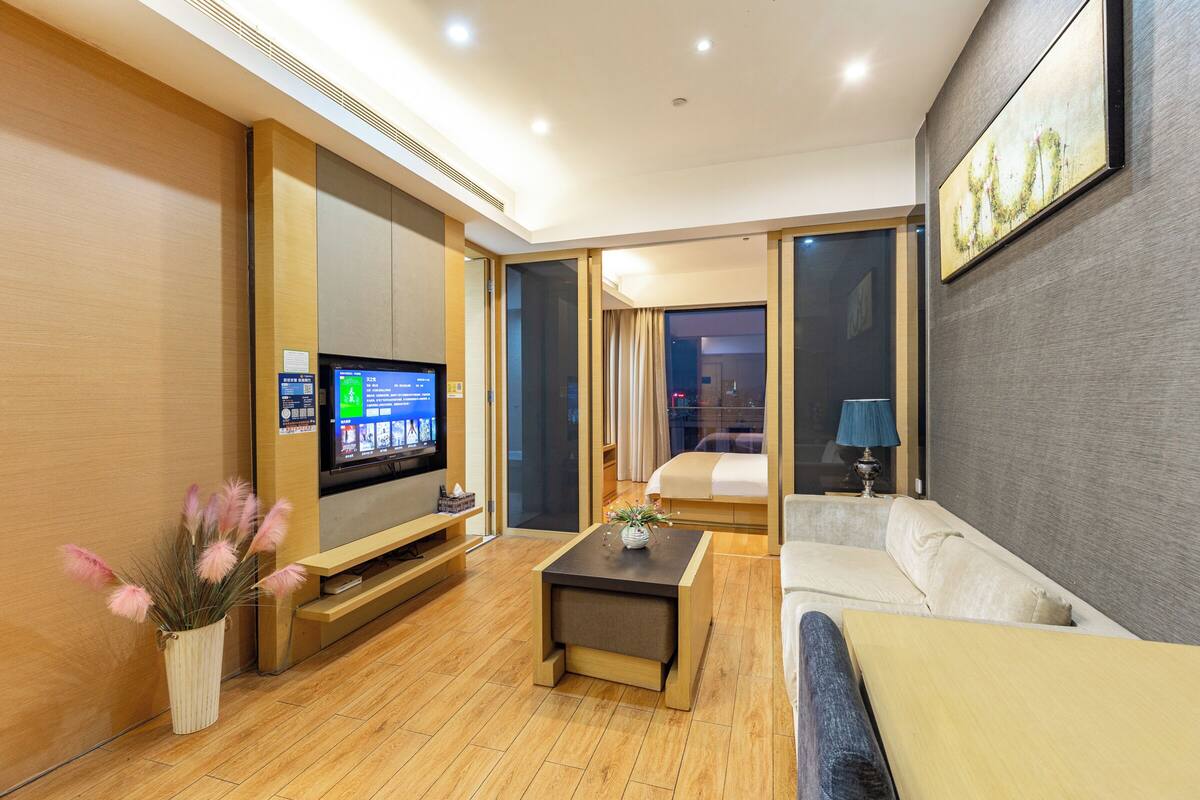 Una habitación de hotel moderna con televisión de pantalla plana, un sofá, una mesa de centro y una cama.