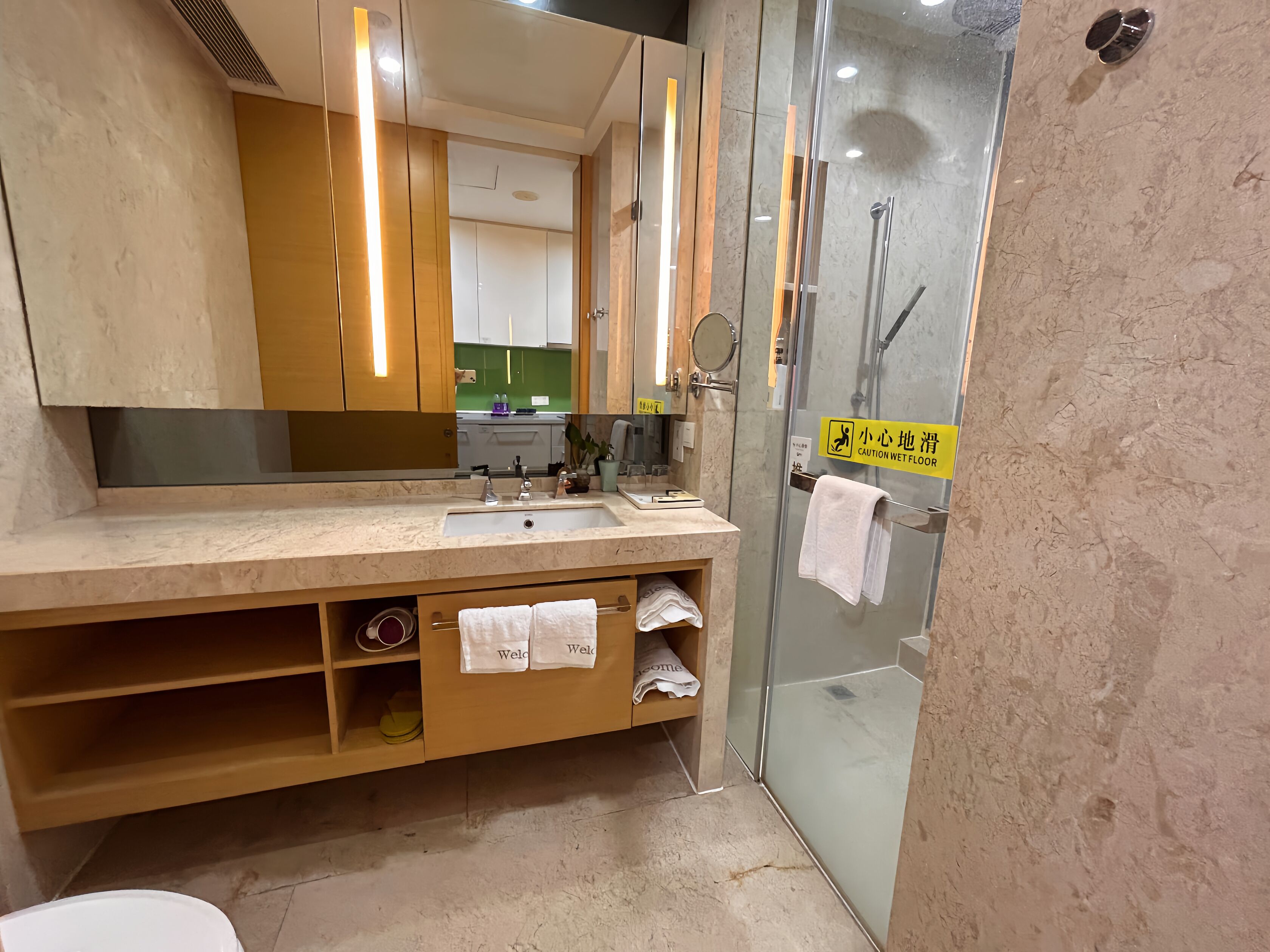 A modern bathroom with a large mirror, a sink, and a glass shower enclosure.