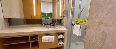 A modern bathroom with a large mirror, a sink, and a glass shower enclosure.