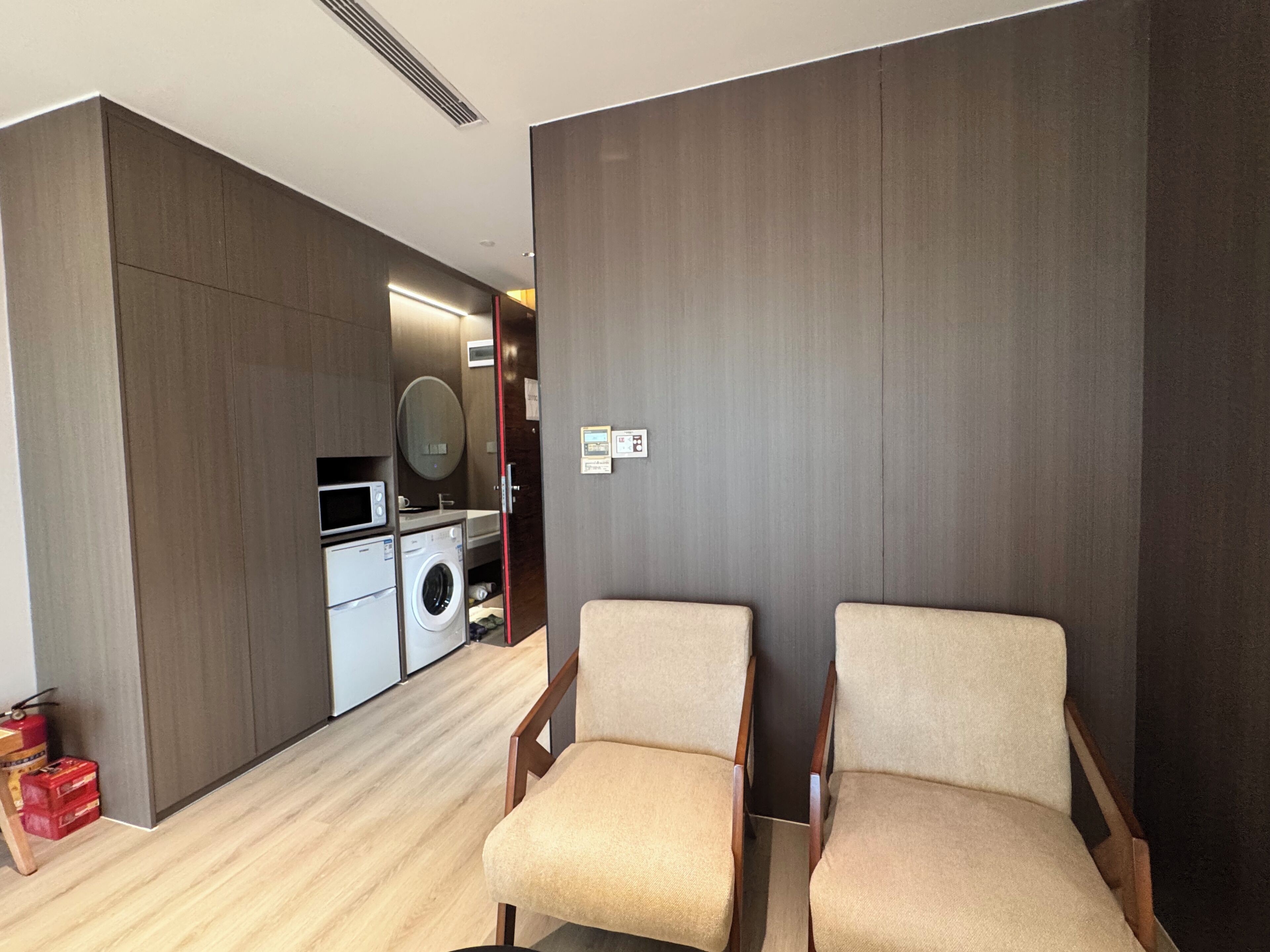 Hotelkamer met een wasmachine, een magnetron en een zithoek met twee stoelen.
