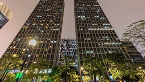 A high-rise building with multiple floors, large windows, and a street lamp in the foreground. - Xingyi International Hotel Poly Store (Guangzhou)