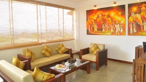 A living room with a sofa set, armchairs, a coffee table, and two paintings on the wall. - Amaara Sky Hotel (Kandy)