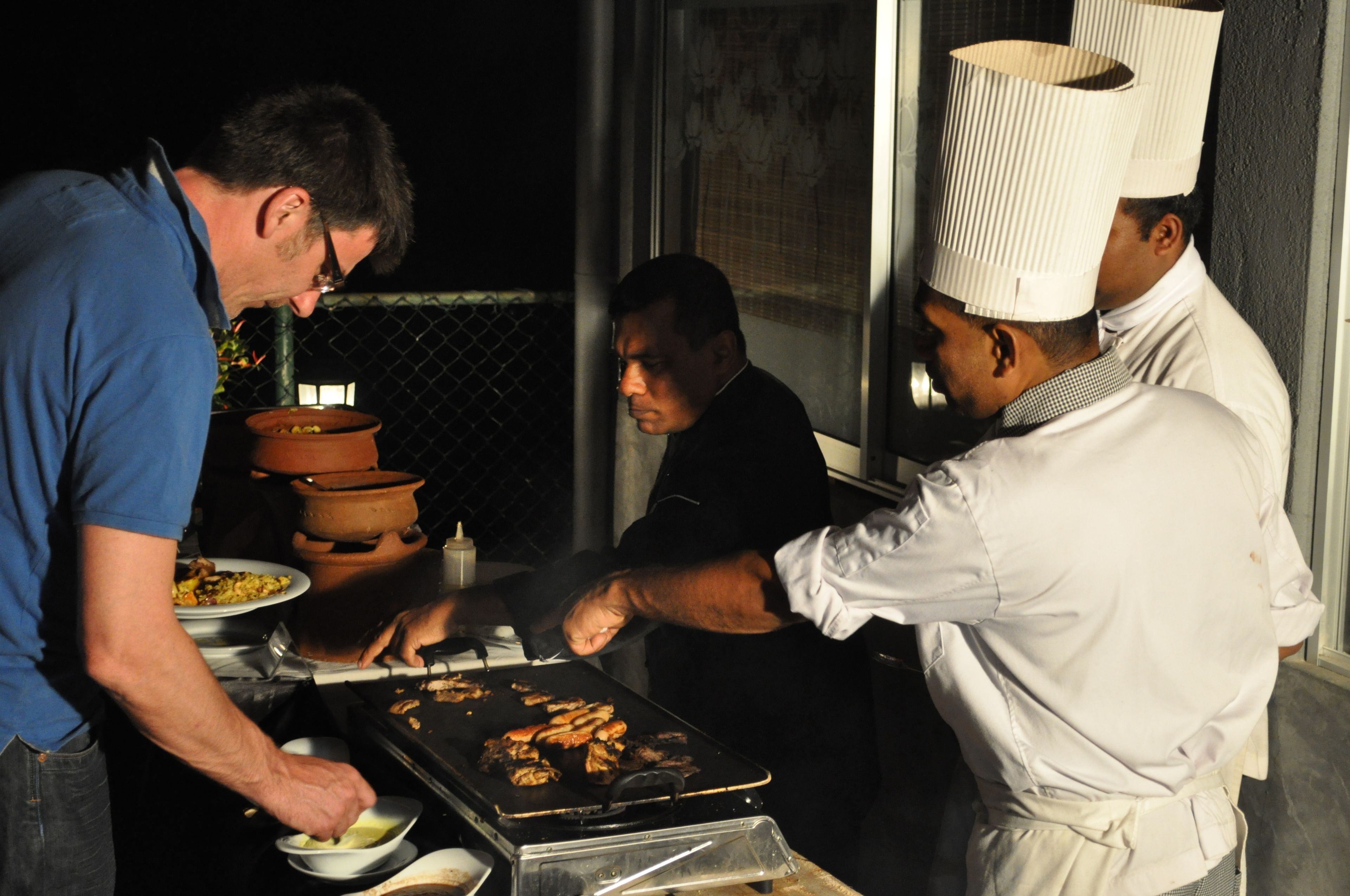 A chef grilling food outdoors at night.