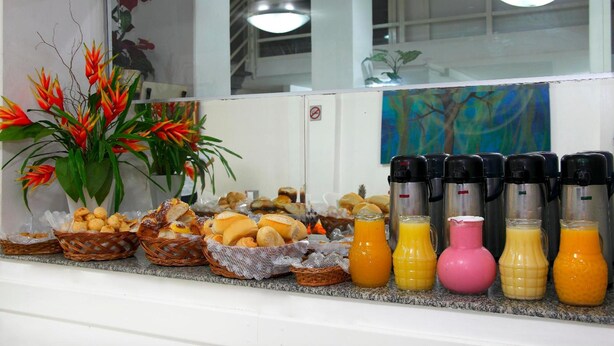 Een ontbijtbuffet met verschillende gebakjes, brood en sapautomaten.