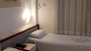 Hotelkamer met twee eenpersoonsbedden, nachtkastje met lamp, wandairco en een schilderij.