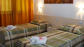 Een hotelkamer met twee eenpersoonsbedden, elk met een gestreept dekbedovertrek en kussens, een nachtkastje met een telefoon, en een schilderij aan de muur.