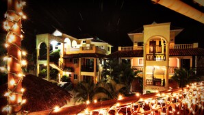 A hotel with multiple balconies, a pool area, and a well-lit facade at night. - Aparta-Hotel Villa Baya (San Rafael del Yuma)