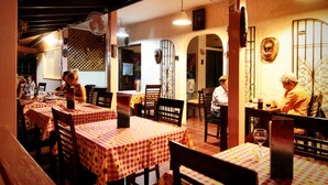 A restaurant with checkered tablecloths, wooden chairs, and fans. - Aparta-Hotel Villa Baya (San Rafael del Yuma)