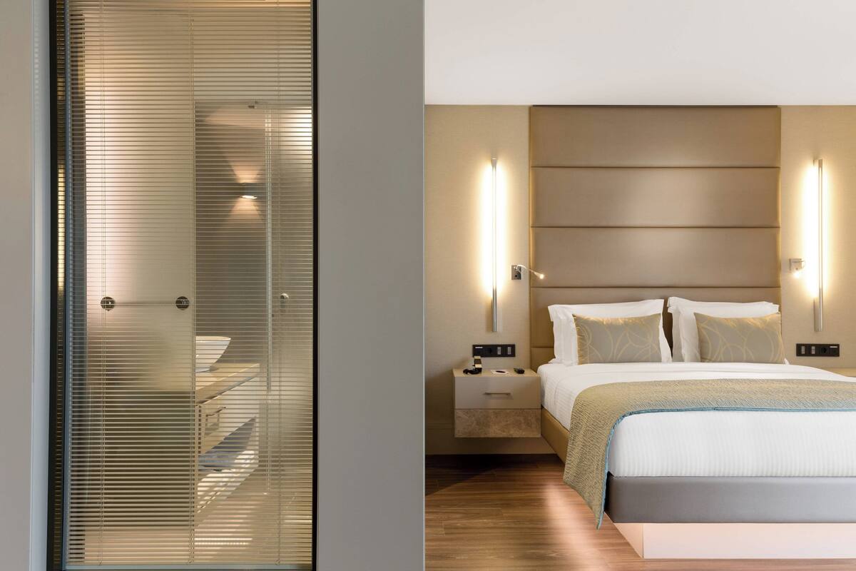 Une chambre moderne avec un lit, des tables de chevet et des luminaires fixés au mur.