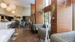 A modern interior with seating areas, a bar, and a kitchen in the background. - AC Hotel Istanbul Macka (Istanbul)