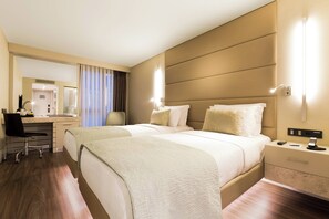 A hotel room with two beds, a desk, and a chair. There is a mirror, a nightstand, and a lamp. - AC Hotel Istanbul Macka (Istanbul)