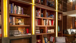 A library with bookshelves, a fireplace, and a round table with a chair. - AC Hotel Istanbul Macka (Istanbul)