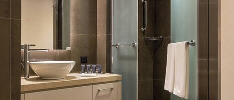 A modern bathroom with a large sink, mirror, and glass shower enclosure.