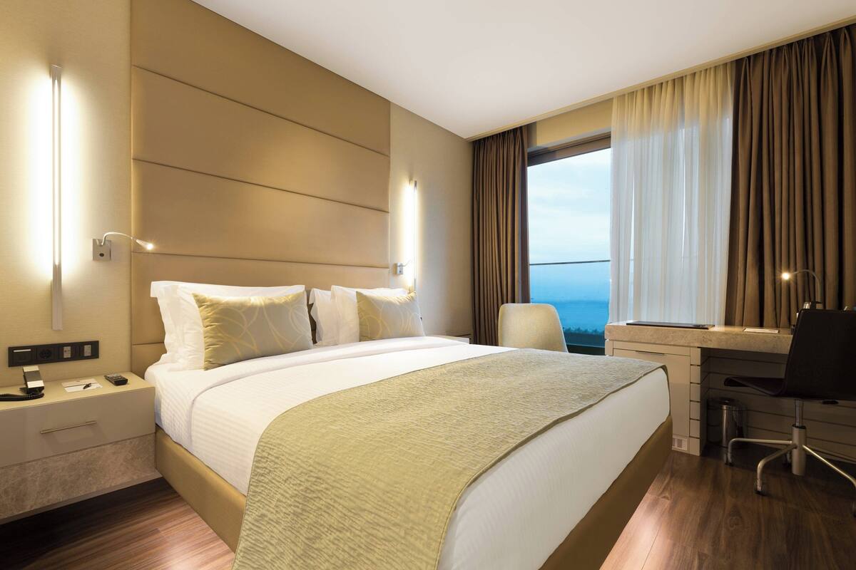 Une chambre d’hôtel avec un grand lit, un bureau et une vue sur l’océan.