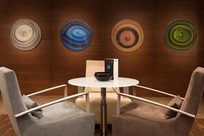 A modern room with a round table, two armchairs, and four abstract wall art pieces. - AC Hotel Istanbul Macka (Istanbul)