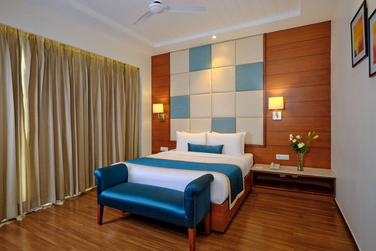 A hotel room with a large bed, a bedside table with a lamp, and a wooden headboard.