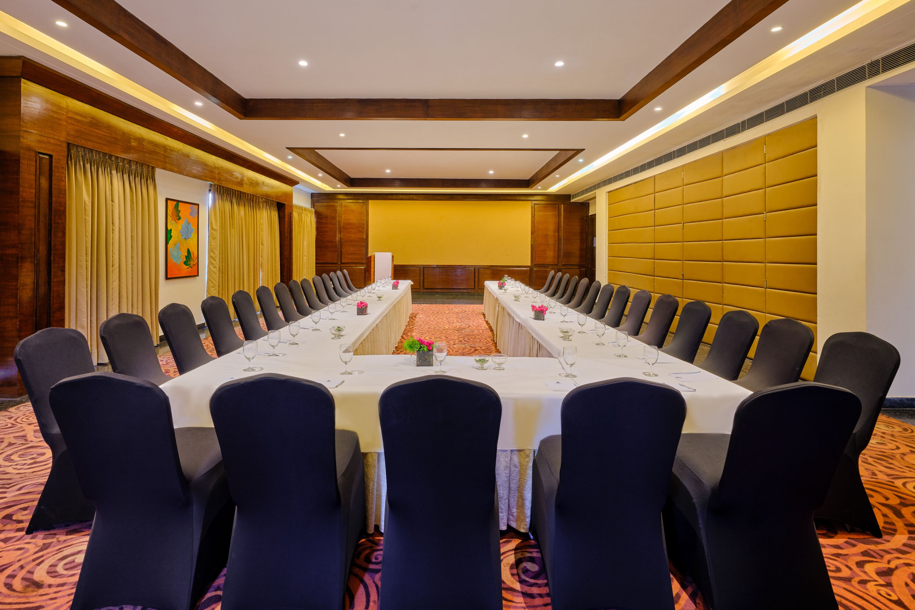 A conference room with a long table, chairs, and a carpeted floor.