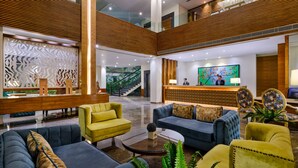A spacious lobby with a reception desk, seating area, and a staircase leading to an upper level. - Best Western Country Woods Ambala (Shahabad)