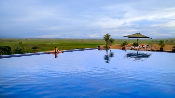 A pool with a view of a green field and a cloudy sky. - Best Western Country Woods Ambala (Shahabad)