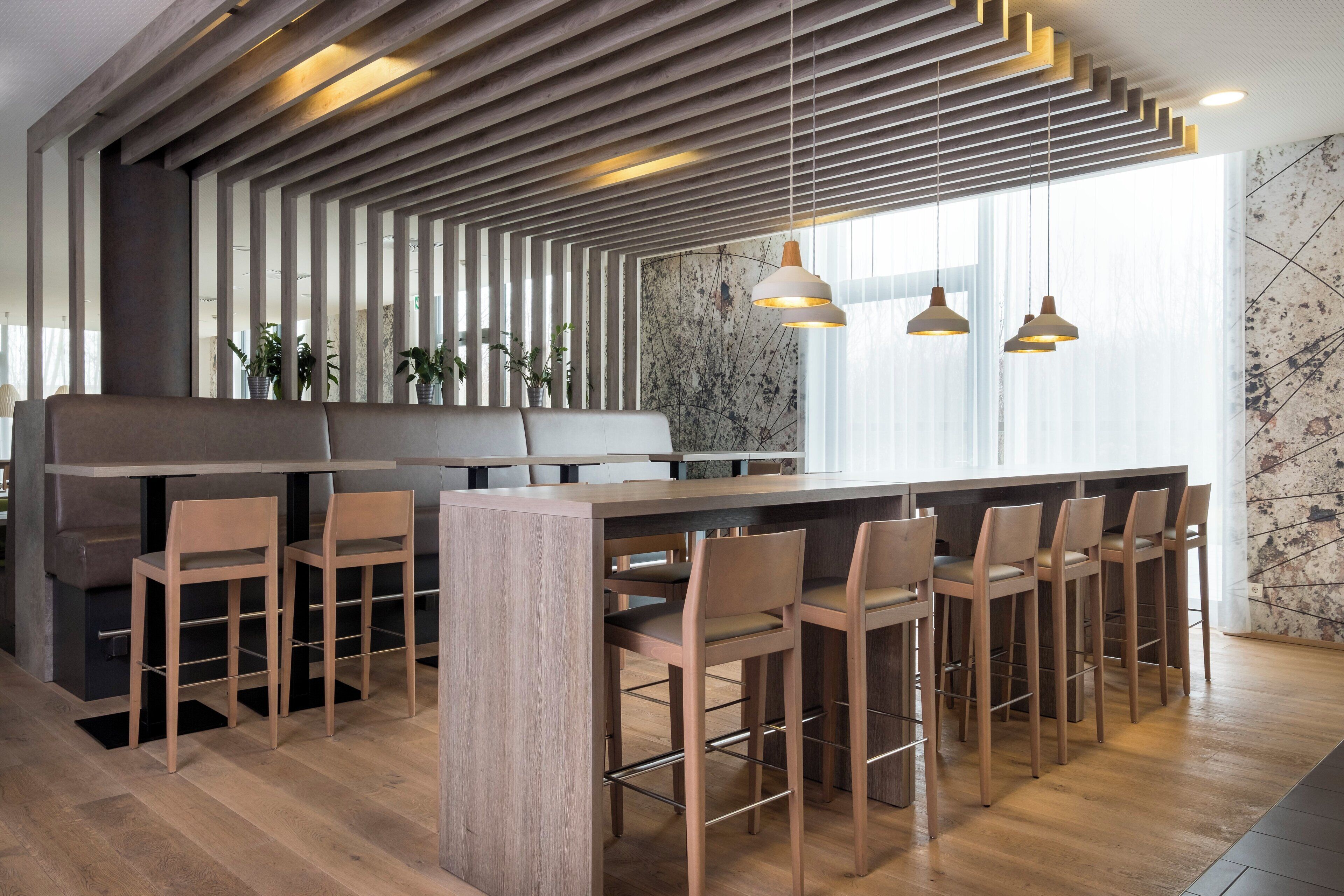 Un área de bar moderna con listones de madera, una barra alargada y varios taburetes.