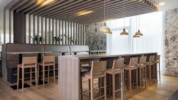 Un área de bar moderna con listones de madera, una barra alargada y varios taburetes.