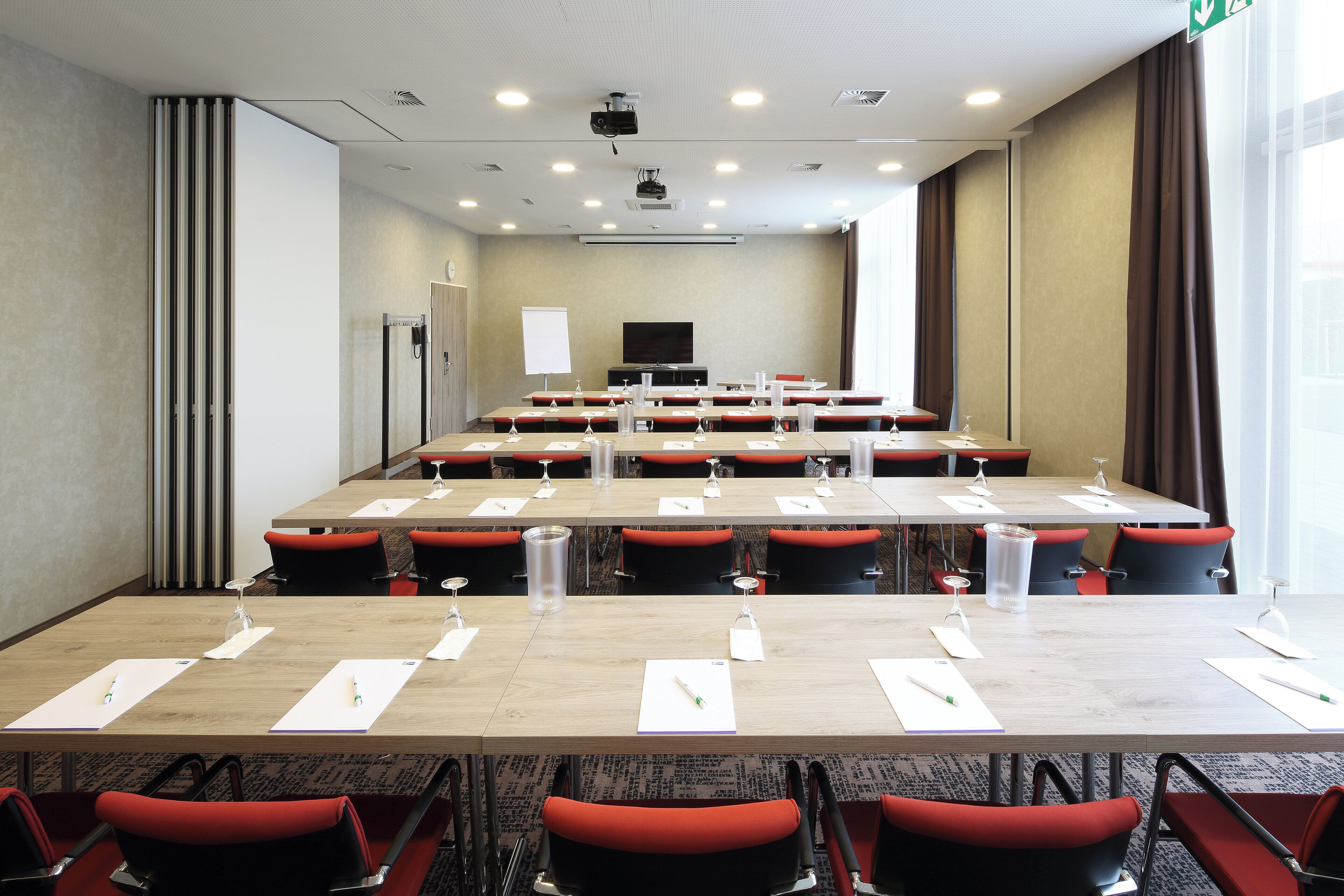 A conference room with multiple tables, chairs, and a projector screen.